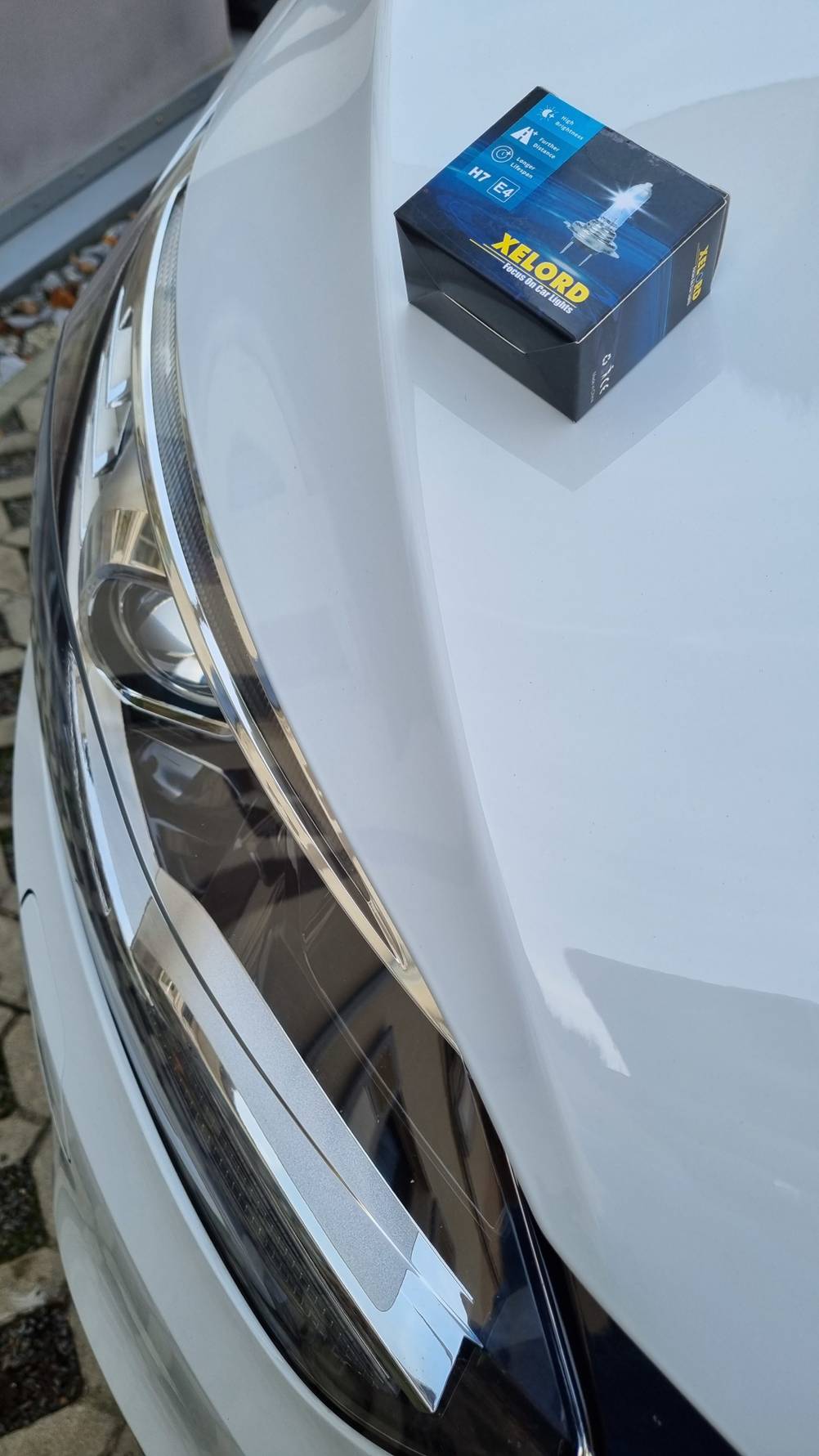 Verpackung einer H7-Birne liegt auf dem Auto.