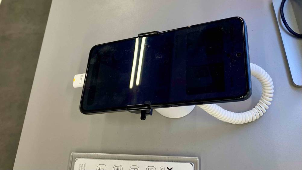 Xiaomi-Handy getestet: Ein ausgeschaltenes Gerät von schräg oben auf einem Ständer in einer Verkaufsfläche.