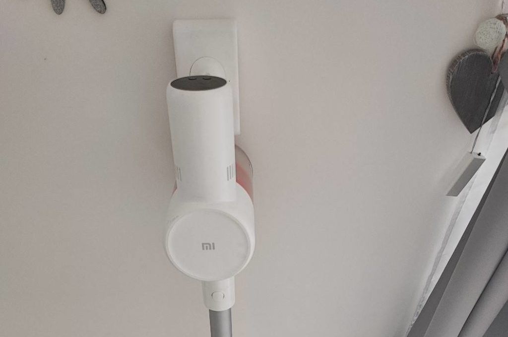 Akku-Staubsauger im Test: ein weißer Mi Vacuum Cleaner G 10 der Marke Xiaomi steht inklusive Zubehör an seiner Wandhalterung in einem hellen Wohnbereich.