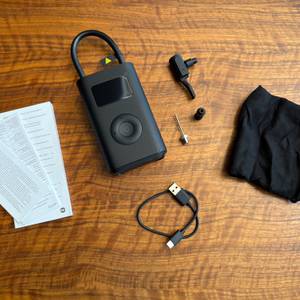 Der Lieferumfang vom Xiaomi Portable Electric Air Compressor 2 liegt auf einem Tisch