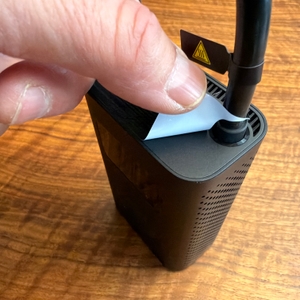 Eine Hand zieht eine Folie vom Xiaomi Portable Electric Air Compressor 2 ab