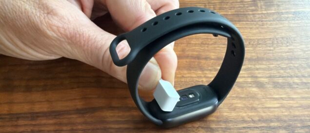 Eine Hand legt das Ladegerät auf das Xiaomi Smart Band 10