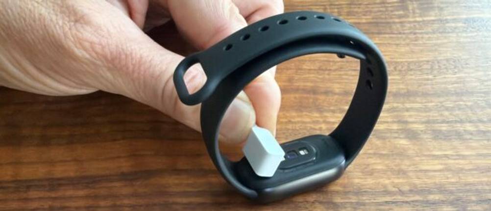 Eine Hand legt das Ladegerät auf das Xiaomi Smart Band 10
