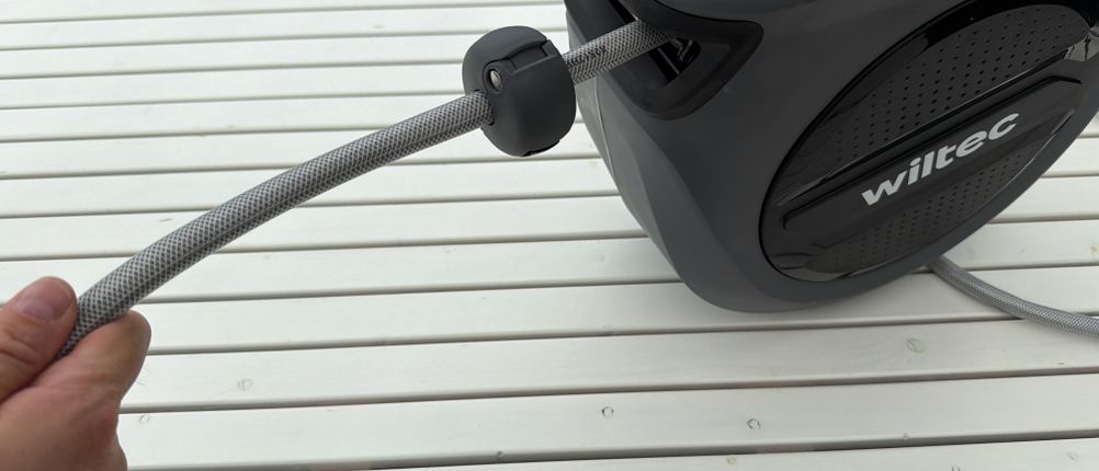 Eine Hand hält die Xpotool-Schlauchtrommel und zieht den Schlauch heraus.