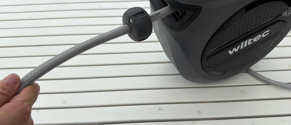 Eine Hand hält die Xpotool-Schlauchtrommel und zieht den Schlauch heraus.