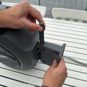 Eine Hand steckt eine Halterung für den Schlauch in die Xpotool-Schlauchtrommel