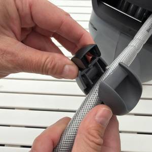 Eine Hand befestigt einen Schlauchstopper am Schlauch von der Xpotool-Schlauchtrommel