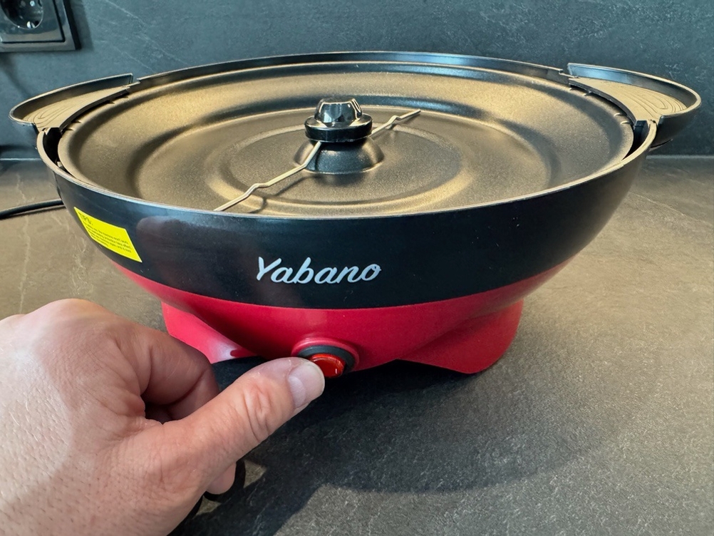 Eine Hand betätigt einen Schalter auf der Yabano-Popcornmaschine