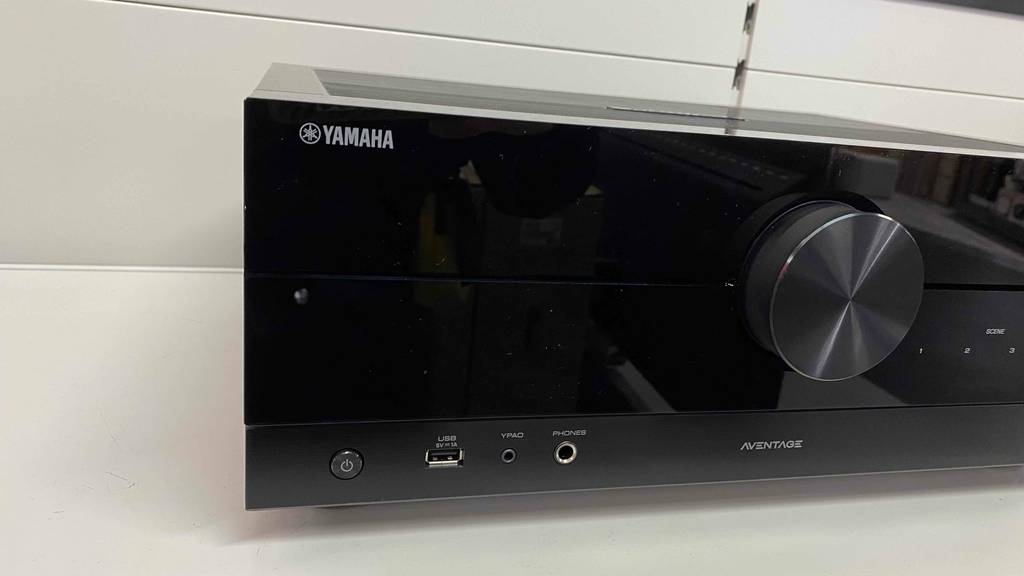 Nahaufnahme eines schwarzen getesteten Yamaha-Receiver: mit Fokus auf den Regler, den Einschaltknopf und die vorderen Anschlussbuchsen.