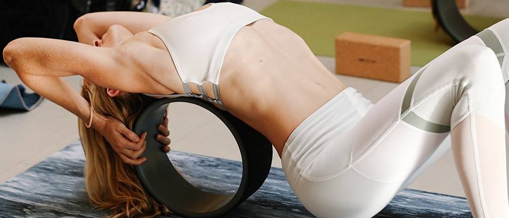 Yoga Wheel Test: Eine Frau macht mit Hilfe eines Yoga Wheels eine Rückenbeuge. 