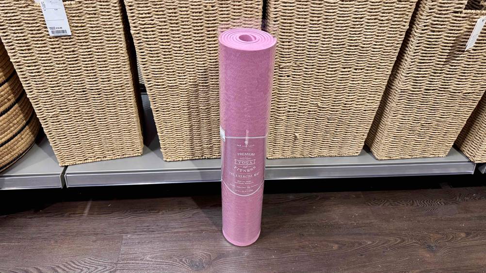 Die getestete Yogamatte TPE steht vor einem Regal mit Körben.
