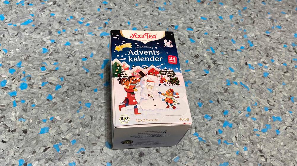 Ein getesteter Adventskalender der Marke Yogi Tea liegt einem blau-grau gesprenkeltem Untergrund.