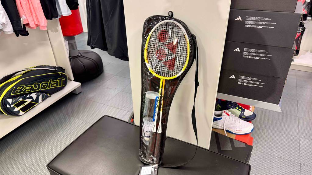 Ein getestetes Badminton-Set lehnt auf einem Lederhocker an einer weißen Wand.