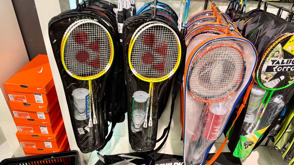 Badminton-Set im Test: Mehrere Sets hängen neben- und hintereinander an einem Wandregal.