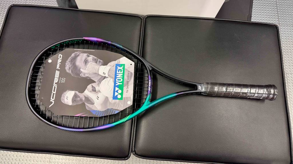 Im Test: Blick von oben auf einen Yonex-Tennisschläger, der quer über zwei Lederhocker liegt.