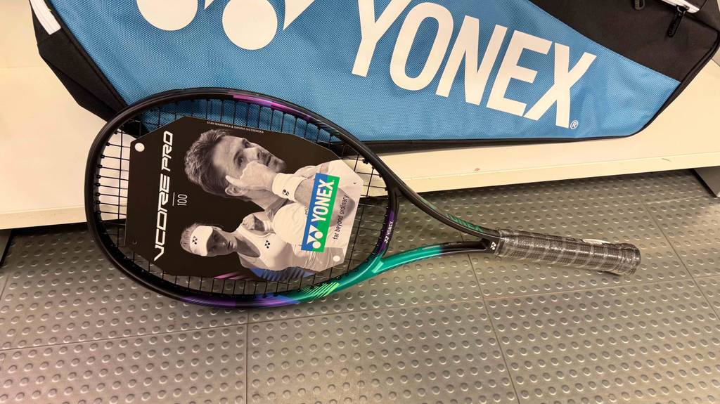 Ein getesteter Yonex-Tennisschläger liegt quer vor einer Aufbewahrungstasche.