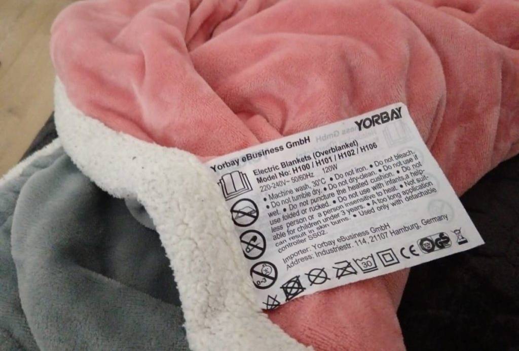 Getestete Heizdecke von Yorbay: Nahaufnahme des Etiketts der grau-rosa-weißen Heizdecke inklusive Waschanleitung.