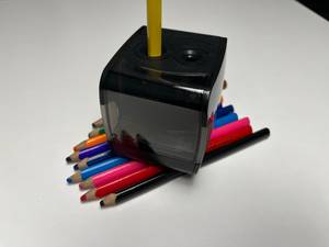 ein elektrischer Anspitzer mit einem Stift darin auf anderen Stiften