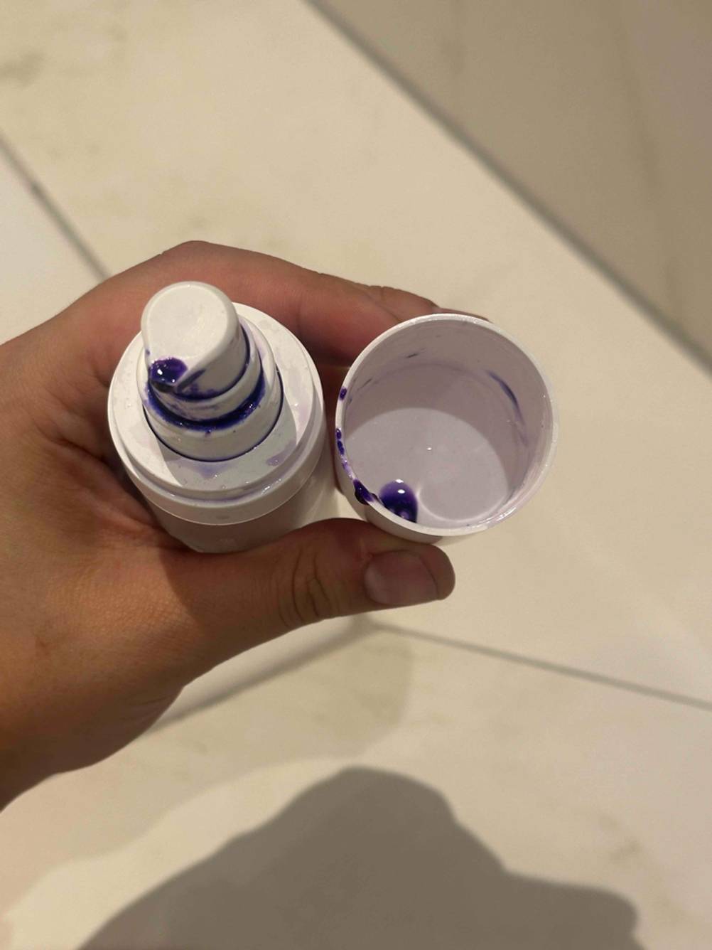 Eine Hand hält eine geöffnete Flasche und den Deckel einer getesteten Zahnaufhellung, Blick von oben.