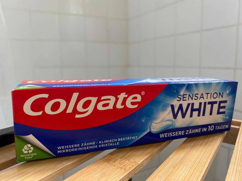Die Originalverapackung der getesteten Zahnpasta gegen Zahnfleischrückgang auf einem Holzregal.