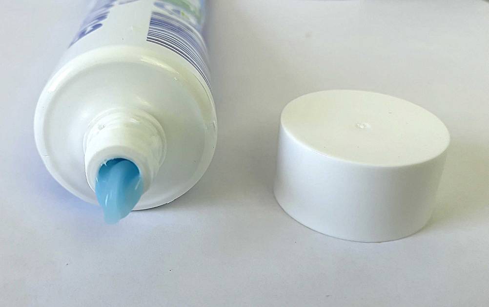 Zahnpasta ohne Mikroplastik getestet: Nahaufnahme der geöffneten Tube mit Deckel daneben.