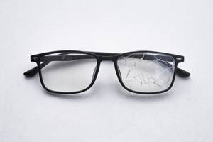Zahnzusatzversicherungen im Test: Eine Brille mit einem gebrochenen Brillenglas liegt auf einem grauen Untergrund.