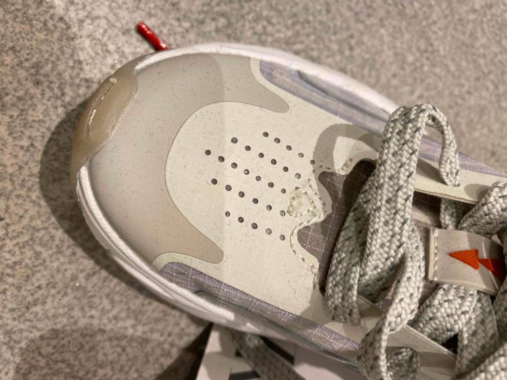 Detailansicht der Schnürsenkel und der verstärkten Spitze weiß-grauer Laufschuhe für Kinder im Test.