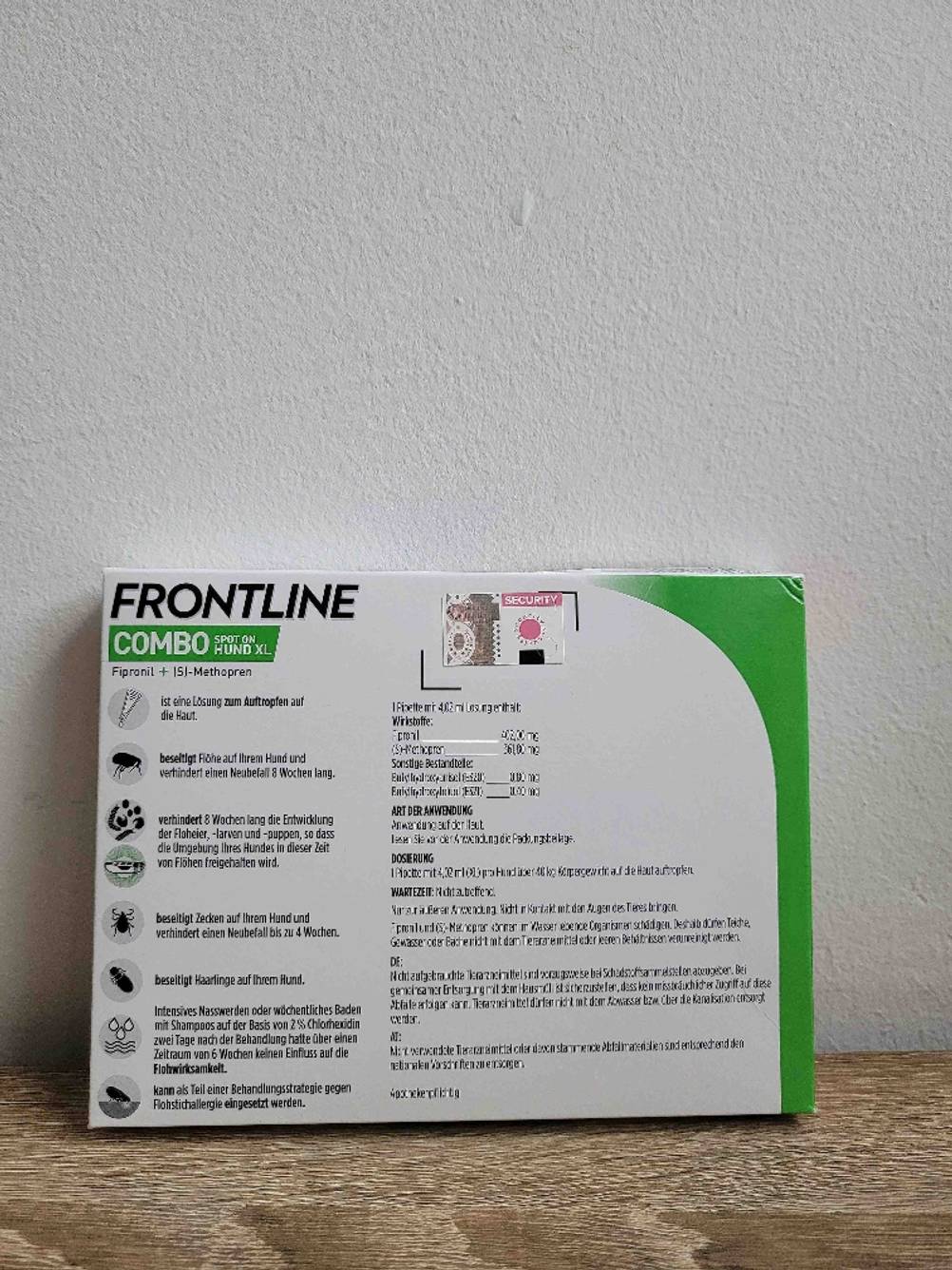 Eine Packung des Zeckenschutzes für den Hund lehnt mit der Rückseite nach vorne an einer hellen Wand.