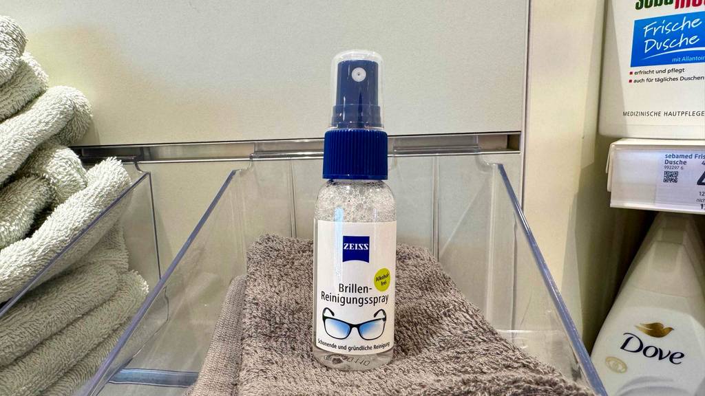 Ein getesteter Brillenreiniger in der Sprühflasche mit alkoholfreier Flüssigkeit steht auf einem Handtuch.
