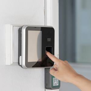 Systeme zur Zeiterfassung im Test: Eine Person bedient eine Stempeluhr mit Fingerabdrucksensor.
