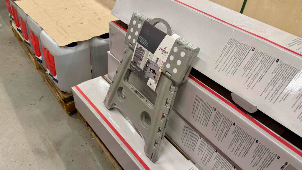 Ein zusammengeklappter Klapphocker lehnt zum testen auf mehrere Kartons.