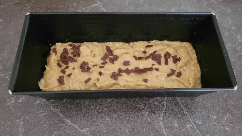 Eine rechteckige, getestete Backform inklusive roher Kuchenmasse steht auf einer Küchen-Arbeitsplatte.