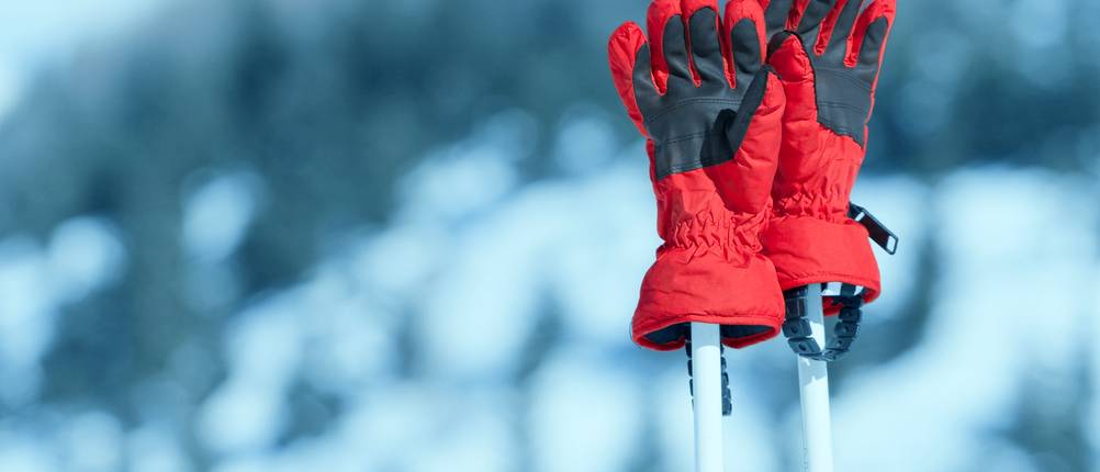Ziener-Handschuhe im Test: Rote Handschuhe auf Ski-Stöcken im Schnee.