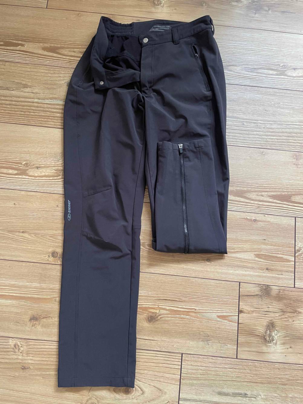 Softshellhose-Damen-Test: Eine getestete Softshellhose für Damen liegt mit einem eingeschlagenen Bein auf einem Holzboden.