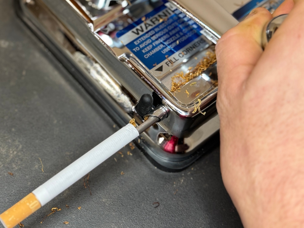 Eine Zigarette wird im Test mit der Zigarettenstopfmaschine von OCB gestopft.