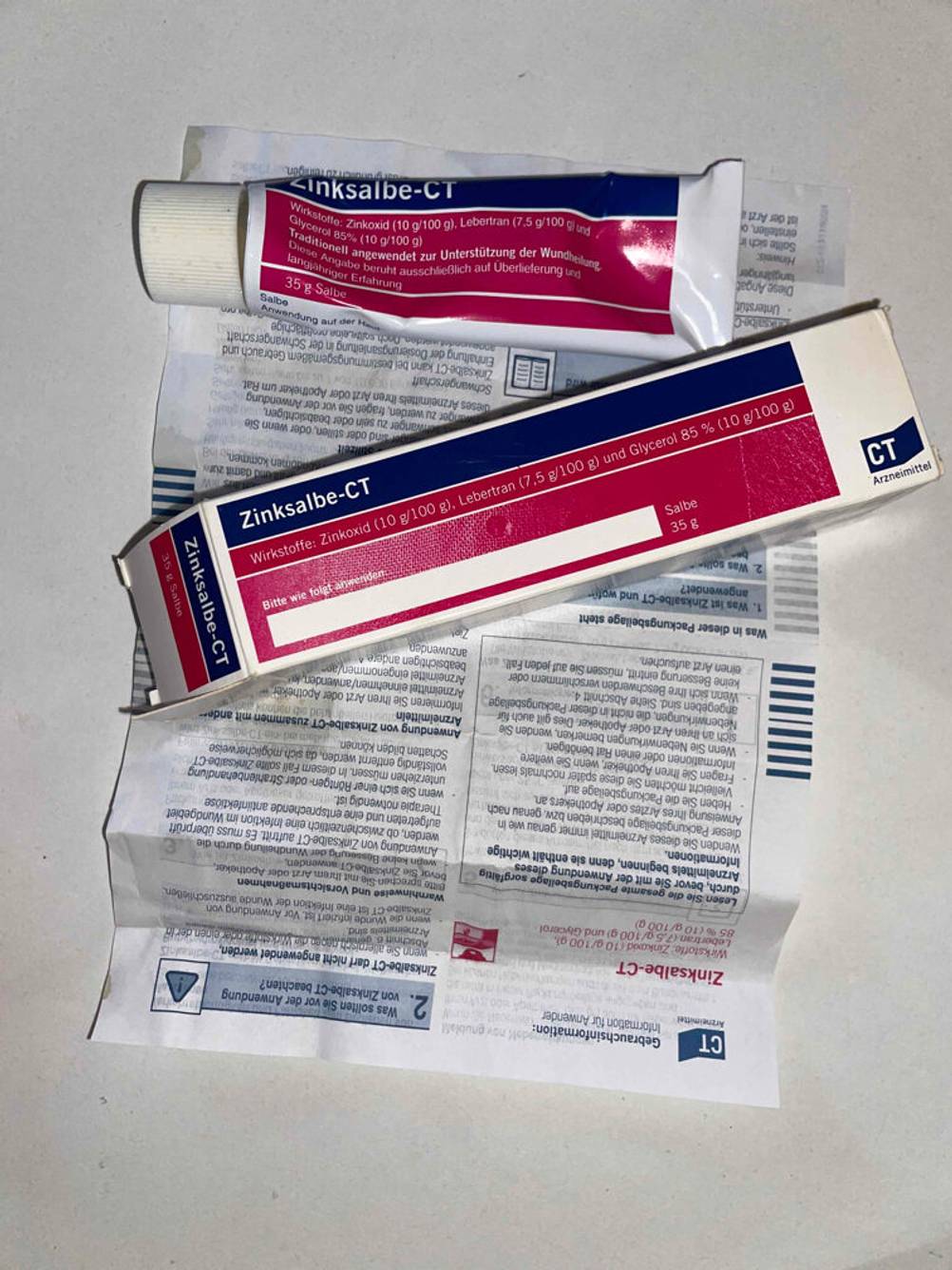 Die Tube und die Verpackung einer Zinksalbe im Test liegen auf dem Beipackzettel.
