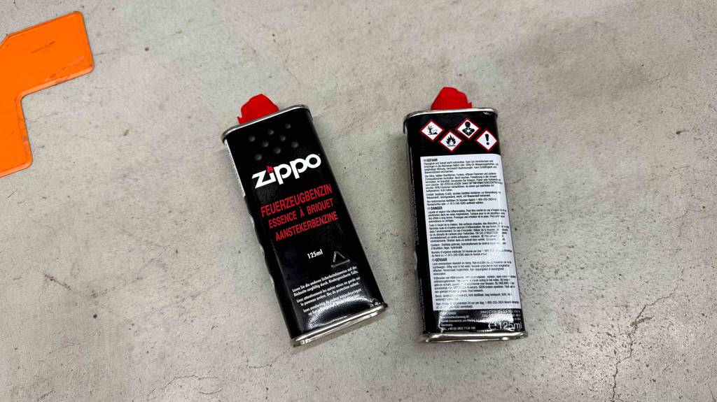 Feuerzeugbenzin getestet: Eine Flasche liegt mit der Rückseite nach oben neben einer zweiten.