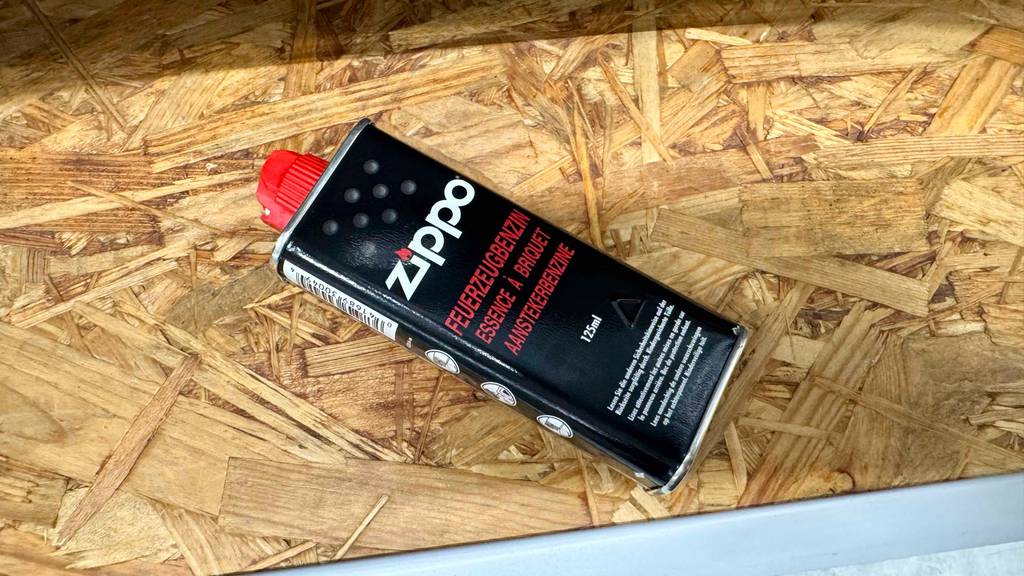 Auf der Seite einer Flasche getestetes Feuerzeugbenzin stehen bebilderte Informationen.