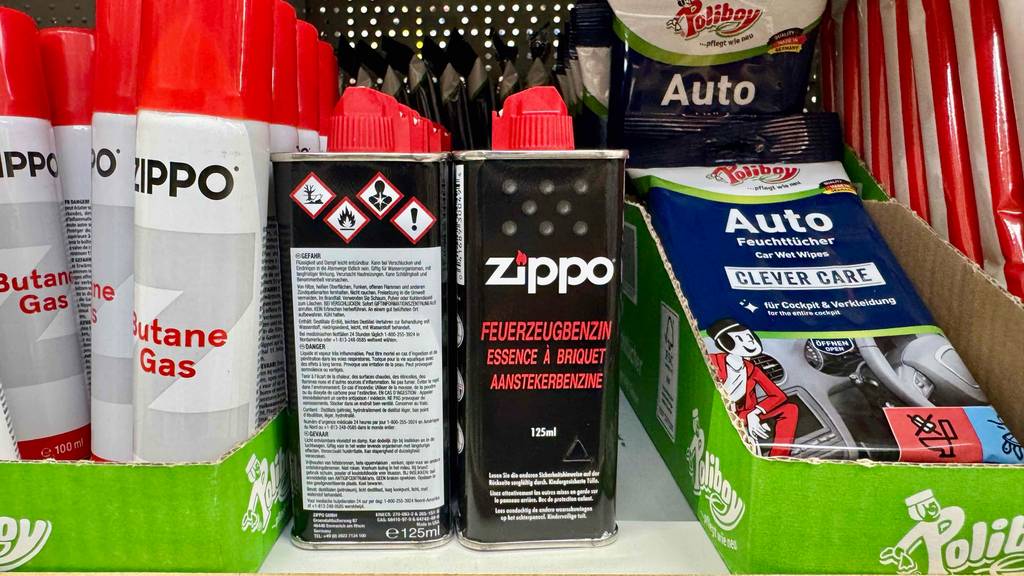 Feuerzeugbenzin im Test: Mehrere Flaschen stehen zwischen anderen Produkten in einem Regal.