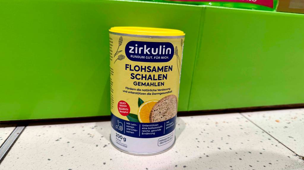Eine Dose getestete Flohsamen steht vor einer grünen Wand.