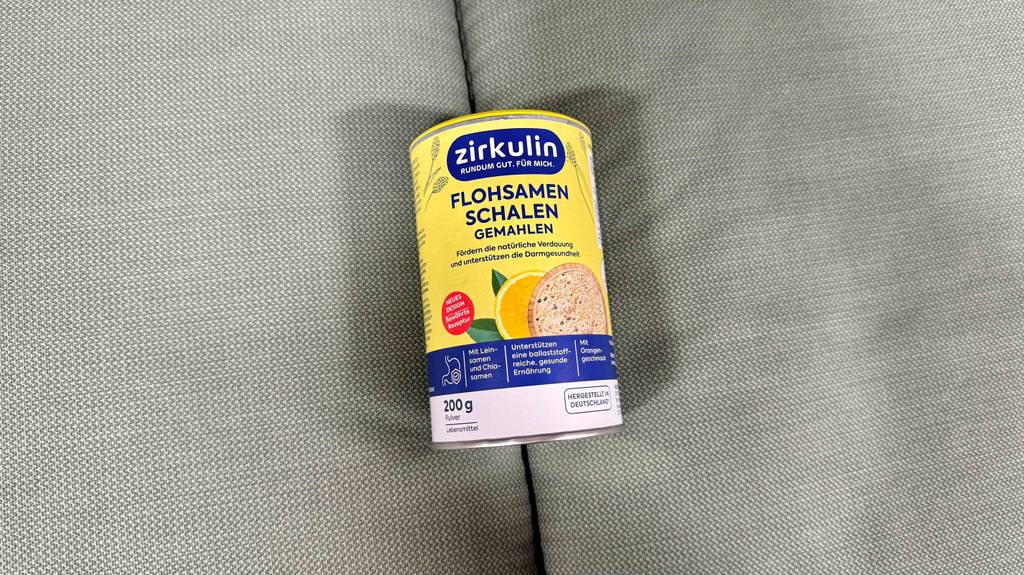 Eine Dose Flohsamen liegt zum testen auf einer grauen Stofffläche.
