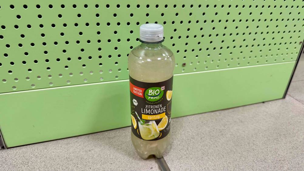 Zitronenlimonade-Test: Eine Flasche steht vor einer grünen Wand auf dem Boden.