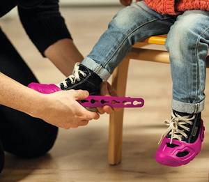 Bobby-Car im Test: Hier werden einem Kind passende Schuhschoner angezogen.