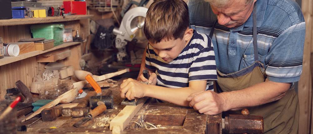 Kinder-Werkbank im Test: ein Junge und ein älterer Herr arbeiten zusammen an einer Werkbank.