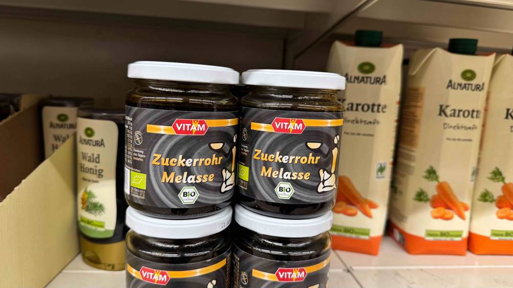 Mehrere Gläser der getesteten Zuckerrohrmelasse stehen neben anderen Produkten in einem Verkaufsregal.