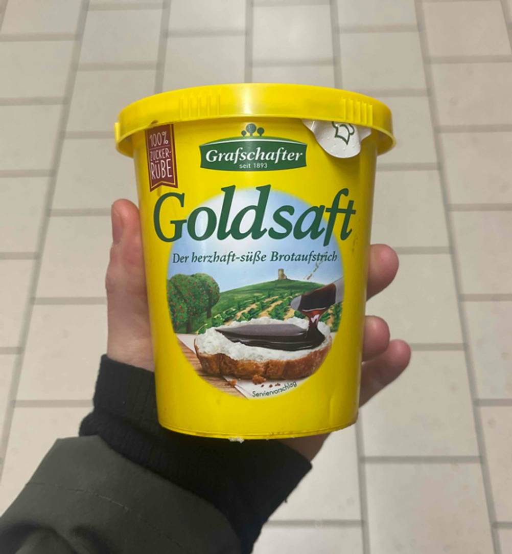 Getestet: Ein Becher Zuckerrübensirup im Test von einer Hand gehalten.