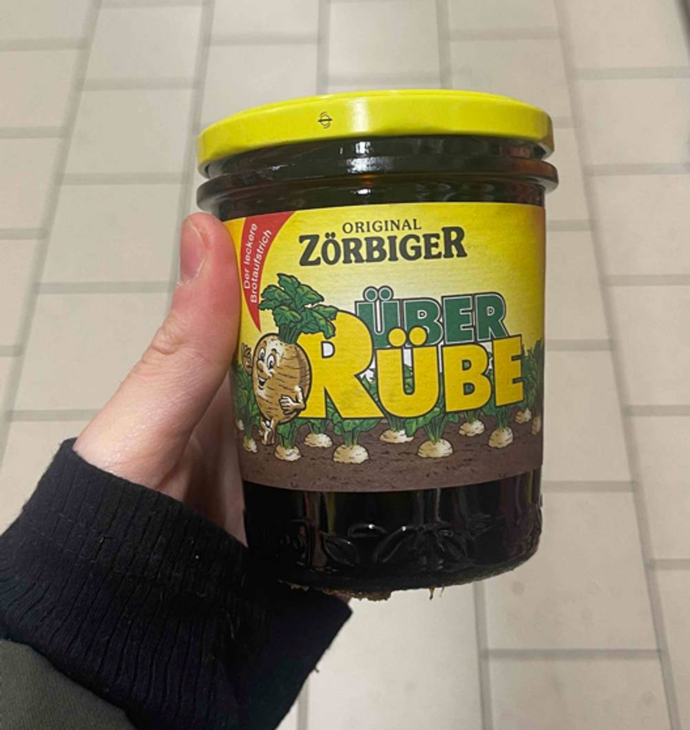 Eine Hand hält ein Glas des getesteten Zuckerrübensirups hoch.