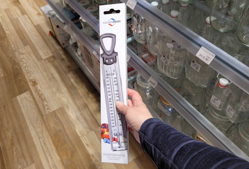 Eine Hand hält das getestete Zuckerthermometer hoch.