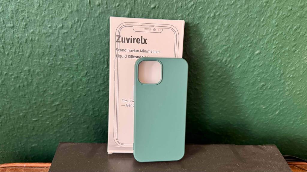 Eine iPhone-13-mini-Hülle lehnt zum testen an eine grüne Wand.