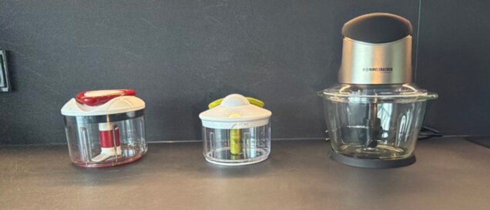 Drei Zwiebelschneider stehen nebeneinander auf einer Küchenarbeitsplatte.